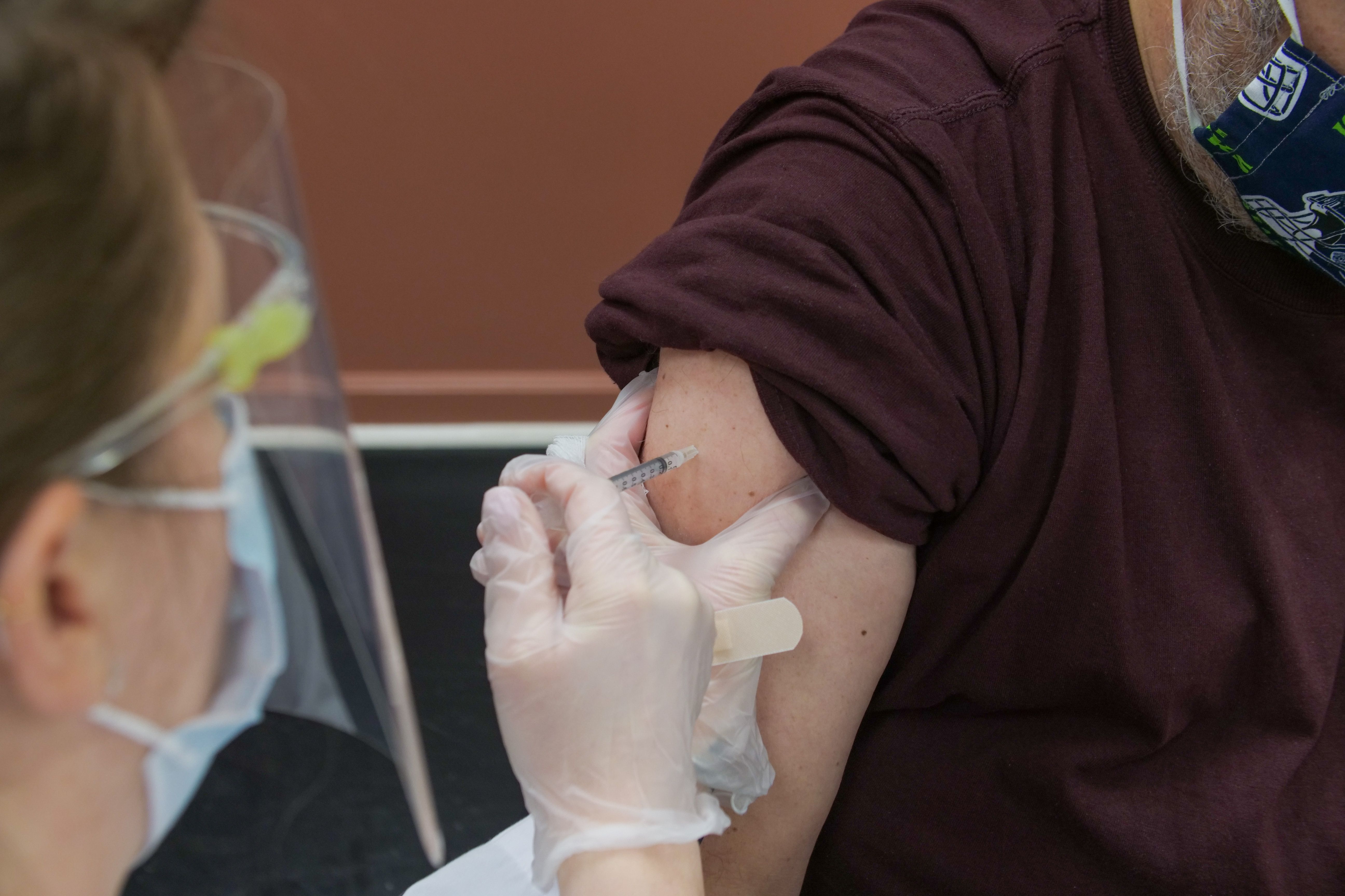 Image of a person being given a shot in their right arm by a nurse.